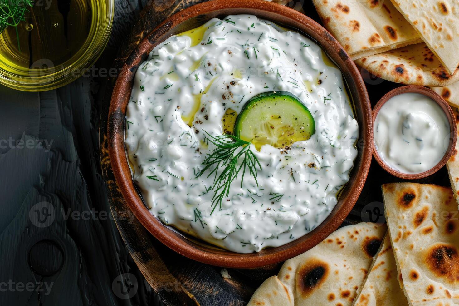 Traditional Greek Tzatziki dip sauce made with cucumber sour cream, Greek yogurt, lemon juice, olive oil and a fresh sprig of dill weed. Served with toasted Pita bread. photo