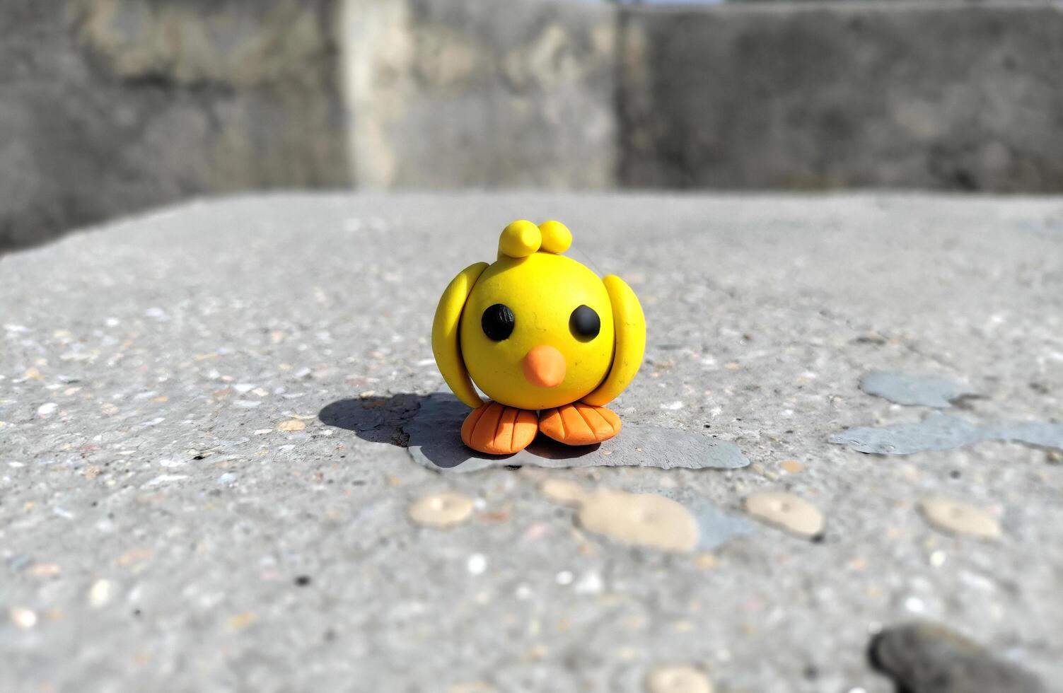 A Cute Yellow Handmade Clay Plasticine Bird Minimalist on stone. Made with Dough. Clay Toy photo