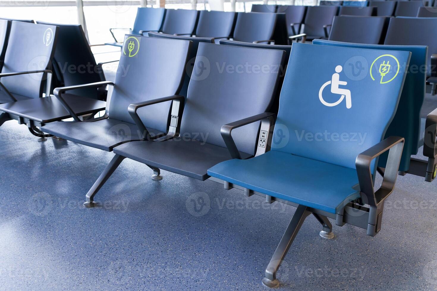 Rows of empty blue seats in public waiting area for people with physical disabilities and people with special needs, charging phone photo