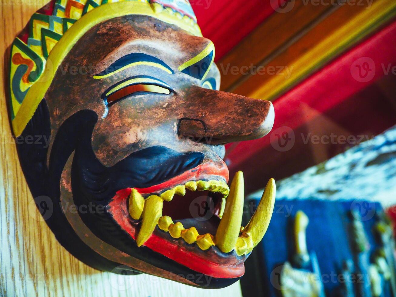 colorful wooden African mask on a wall with big fangs and big nose photo