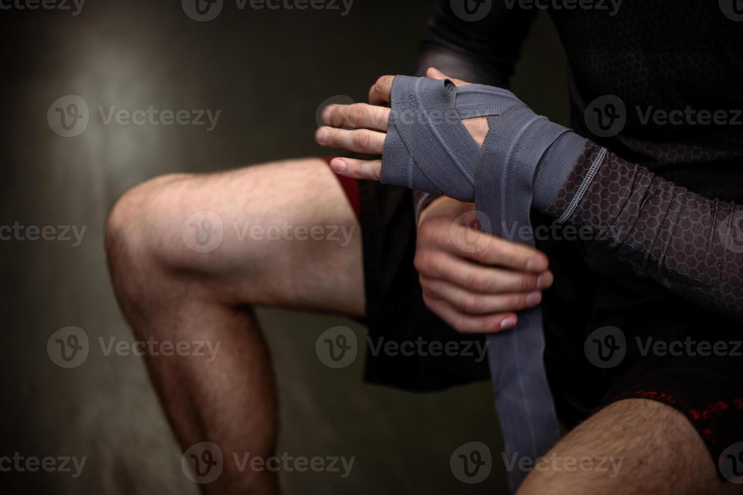 Boxer securing handwraps around wrists before sparring match photo