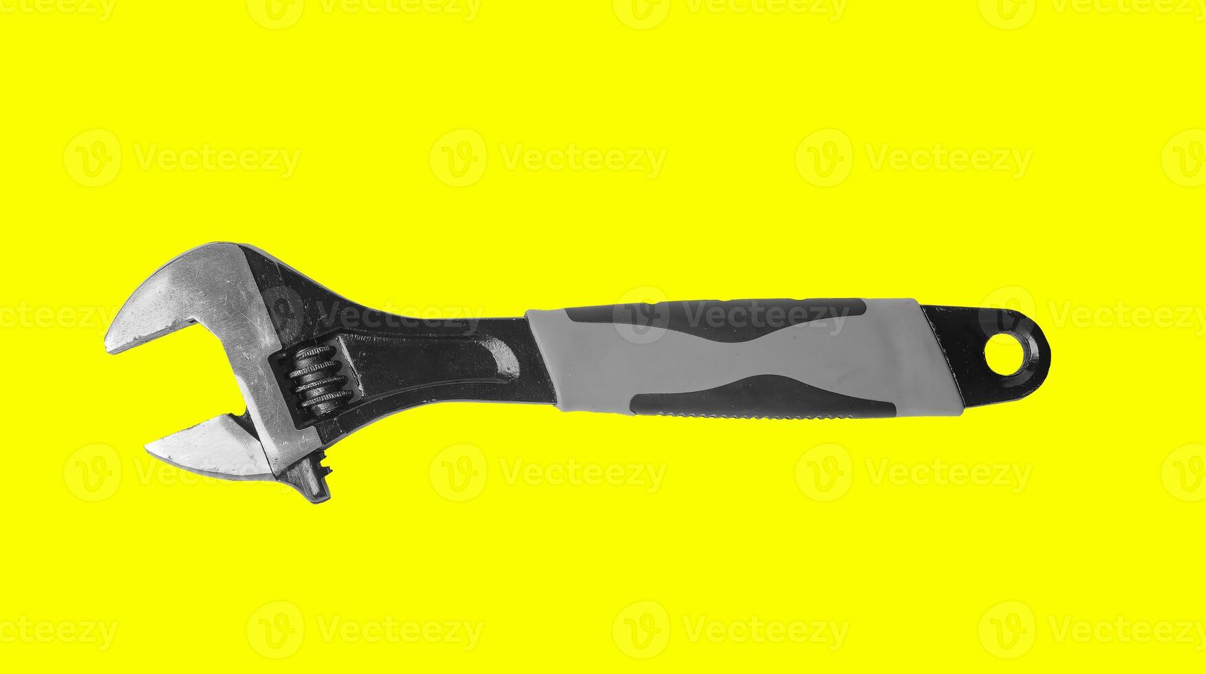 Mechanic with wrench, adjustable spanner in hand on yellow background. Old steel tools, mechanical photo