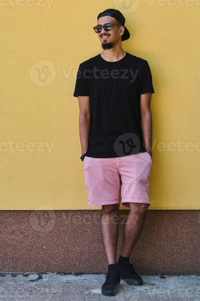 Middle Eastern Teenager Leaning Against Yellow Wall in Casual Attire photo
