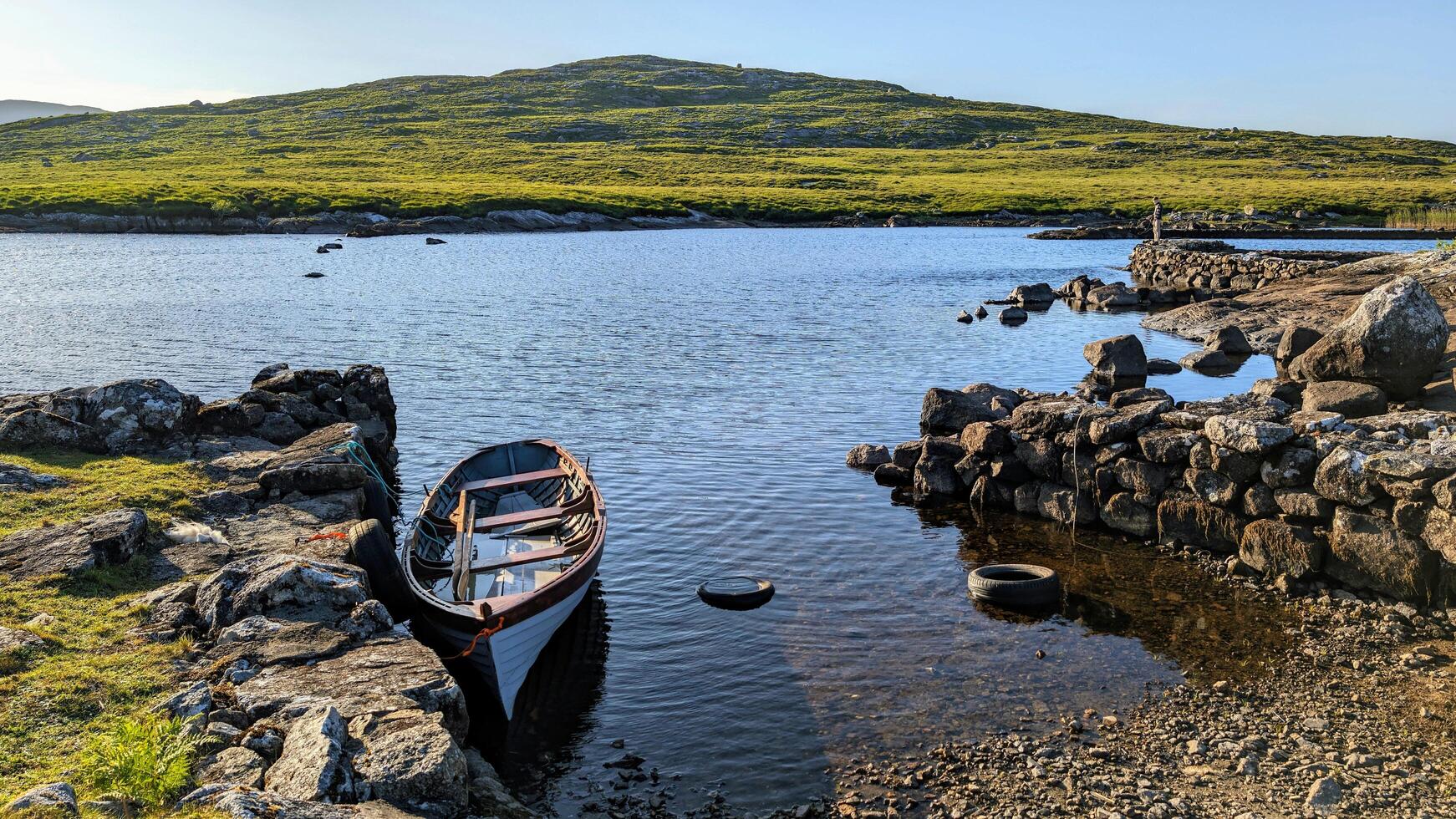 Old wooden fishing boat in lake by Fisherman's hut with mountains in background at Connemara, Galway, Ireland photo