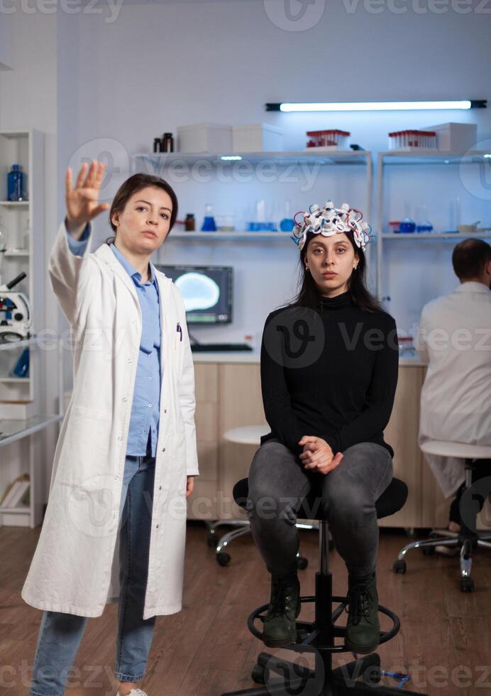 Portrait of neurologist scientist standing beside woman patient with medical eeg scanner during neuroscience experiment in clinical laboratory. Team of researcher analyzing brain activity evolution photo