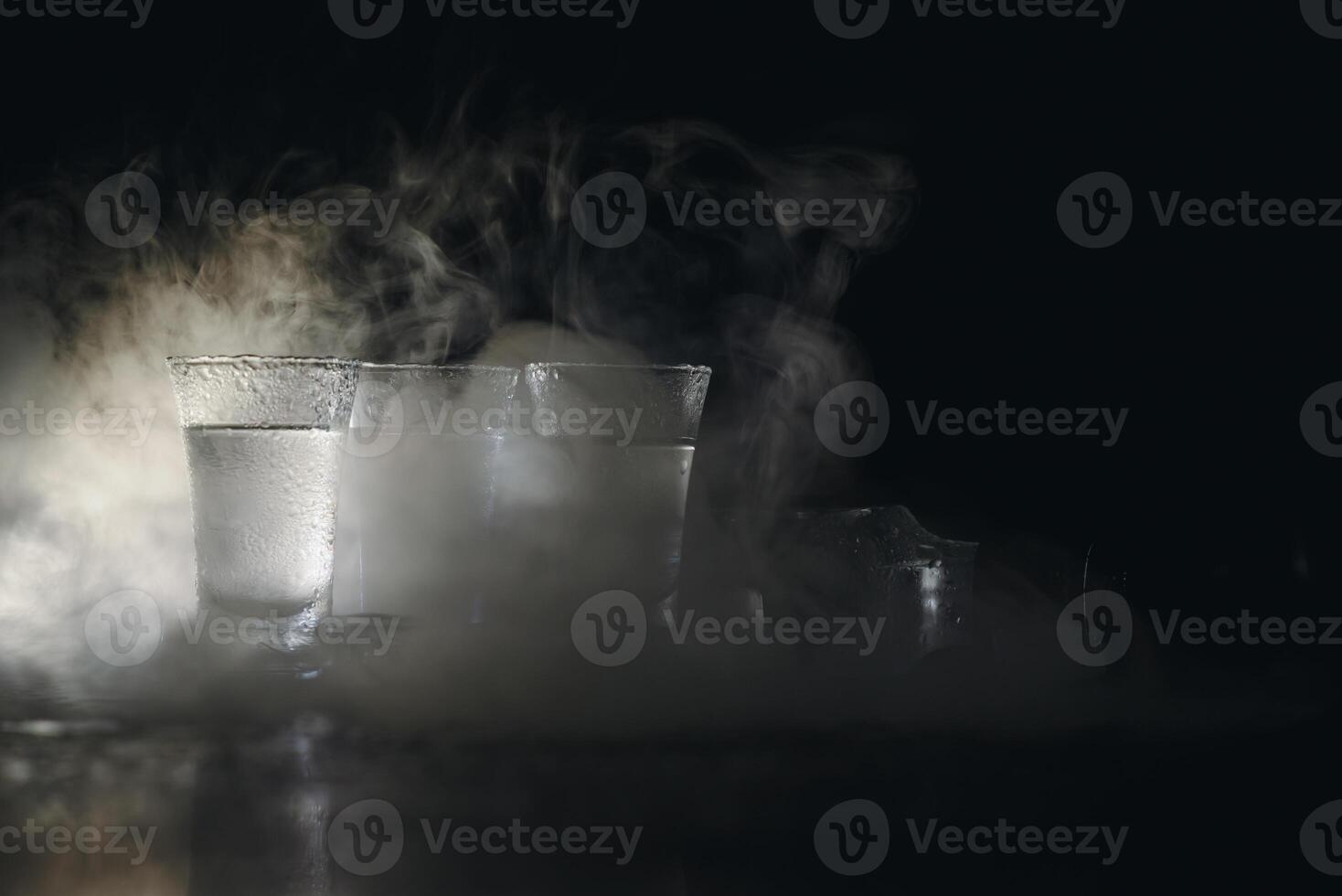 Vodka in shot glasses on dark background photo