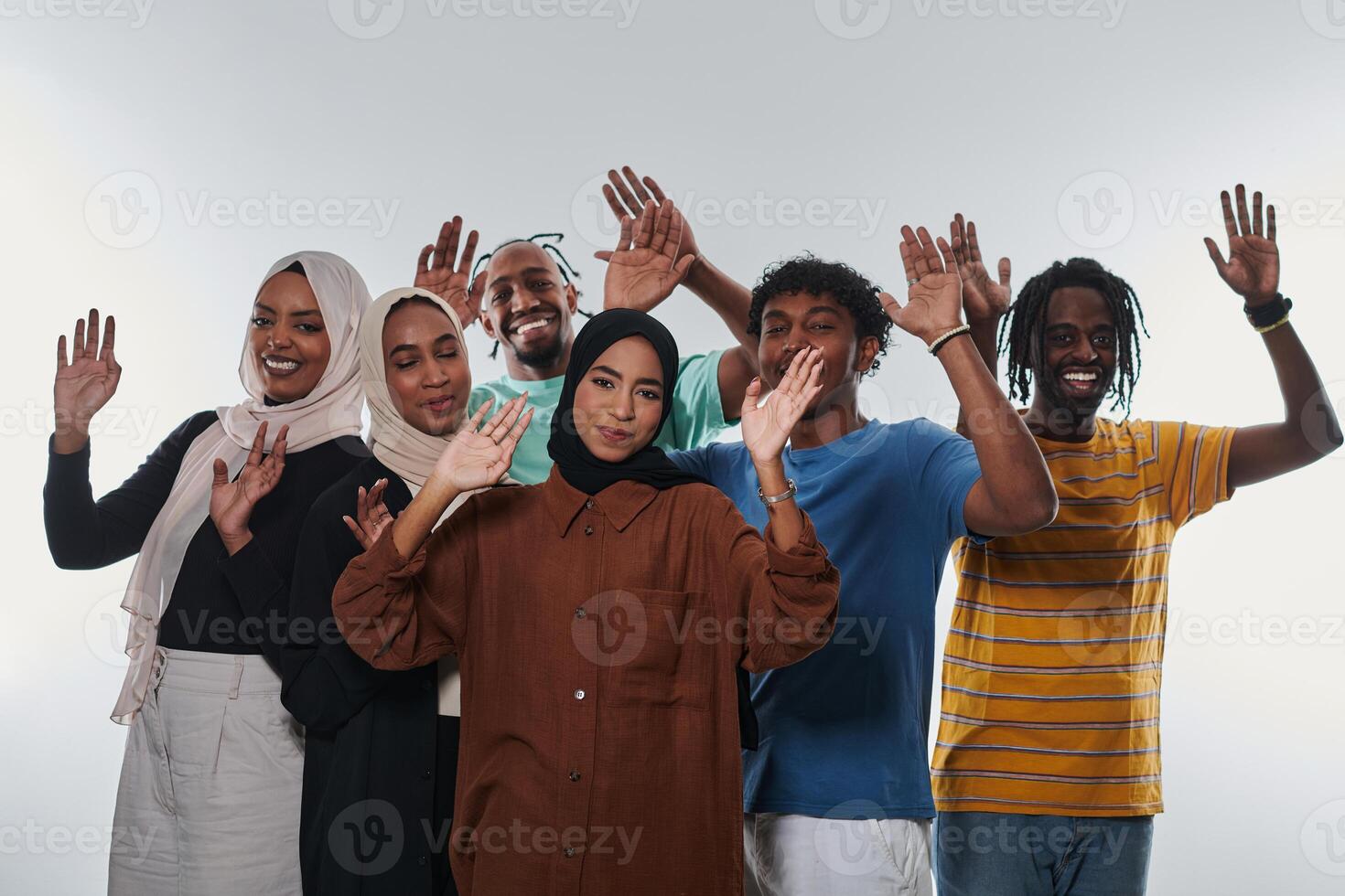 A jubilant and diverse group, including an African American man and hijab-wearing girls, exuberantly wave and celebrate, embodying the vibrancy of student life against a white backdrop, symbolizing photo