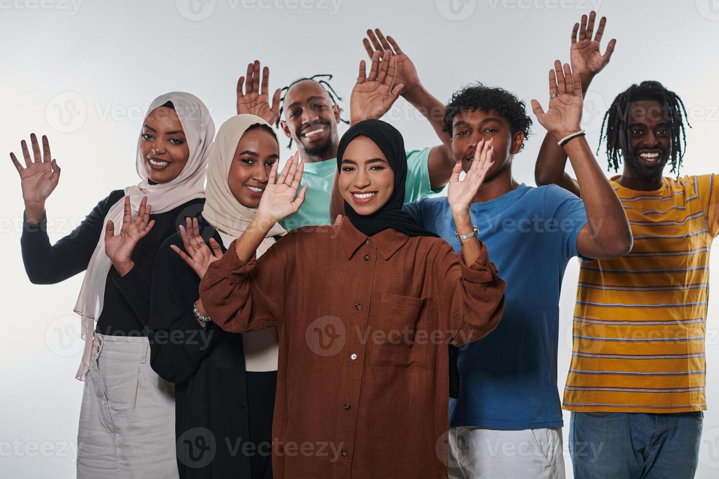 A jubilant and diverse group, including an African American man and hijab-wearing girls, exuberantly wave and celebrate, embodying the vibrancy of student life against a white backdrop, symbolizing photo
