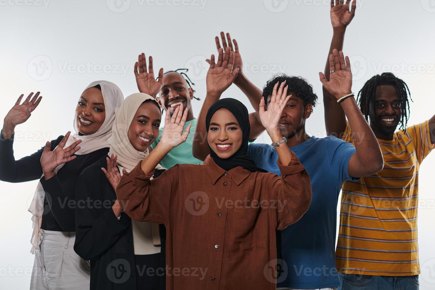 A jubilant and diverse group, including an African American man and hijab-wearing girls, exuberantly wave and celebrate, embodying the vibrancy of student life against a white backdrop, symbolizing photo
