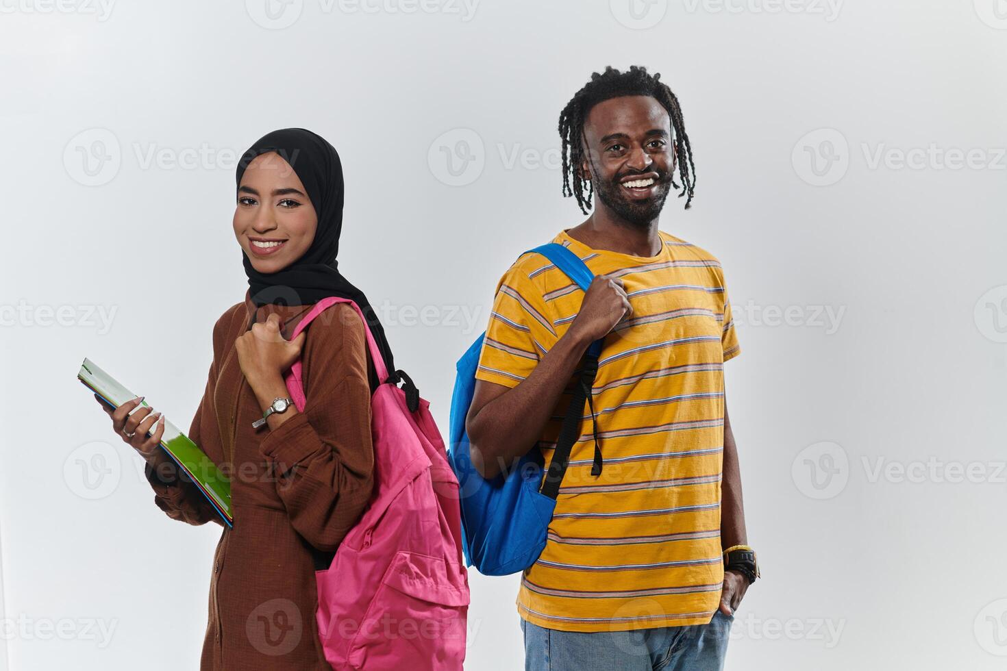 Against a clean white background, two students, an African American young man and a hijab-wearing woman, collaboratively use laptops in a display of technological empowerment and inclusive education photo