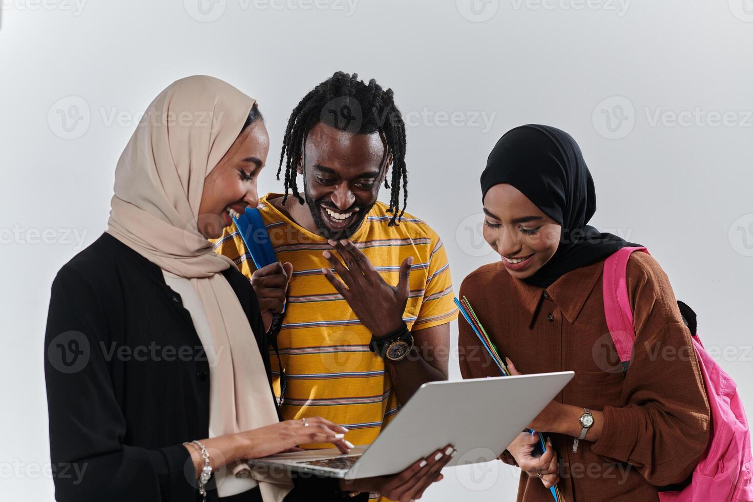 A group of students, including an African American student and two hijab-wearing women, stand united against a pristine white background, symbolizing a harmonious blend of cultures and backgrounds in photo