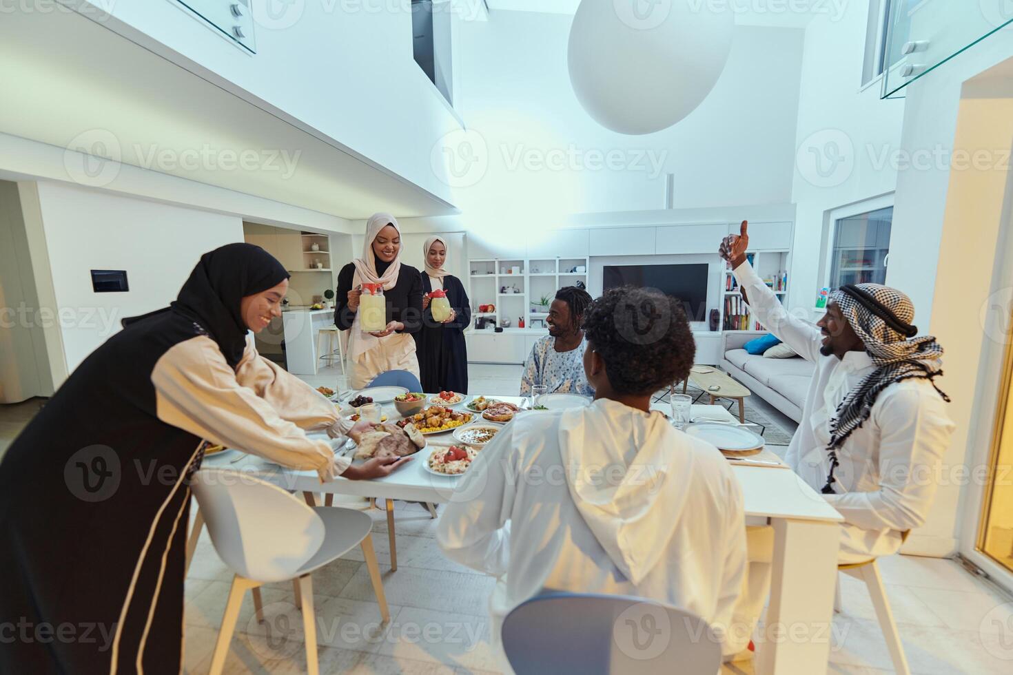 In the sacred month of Ramadan, a Muslim family joyously comes together around a table, eagerly awaiting the communal iftar, engaging in the preparation of a shared meal, and uniting in anticipation photo