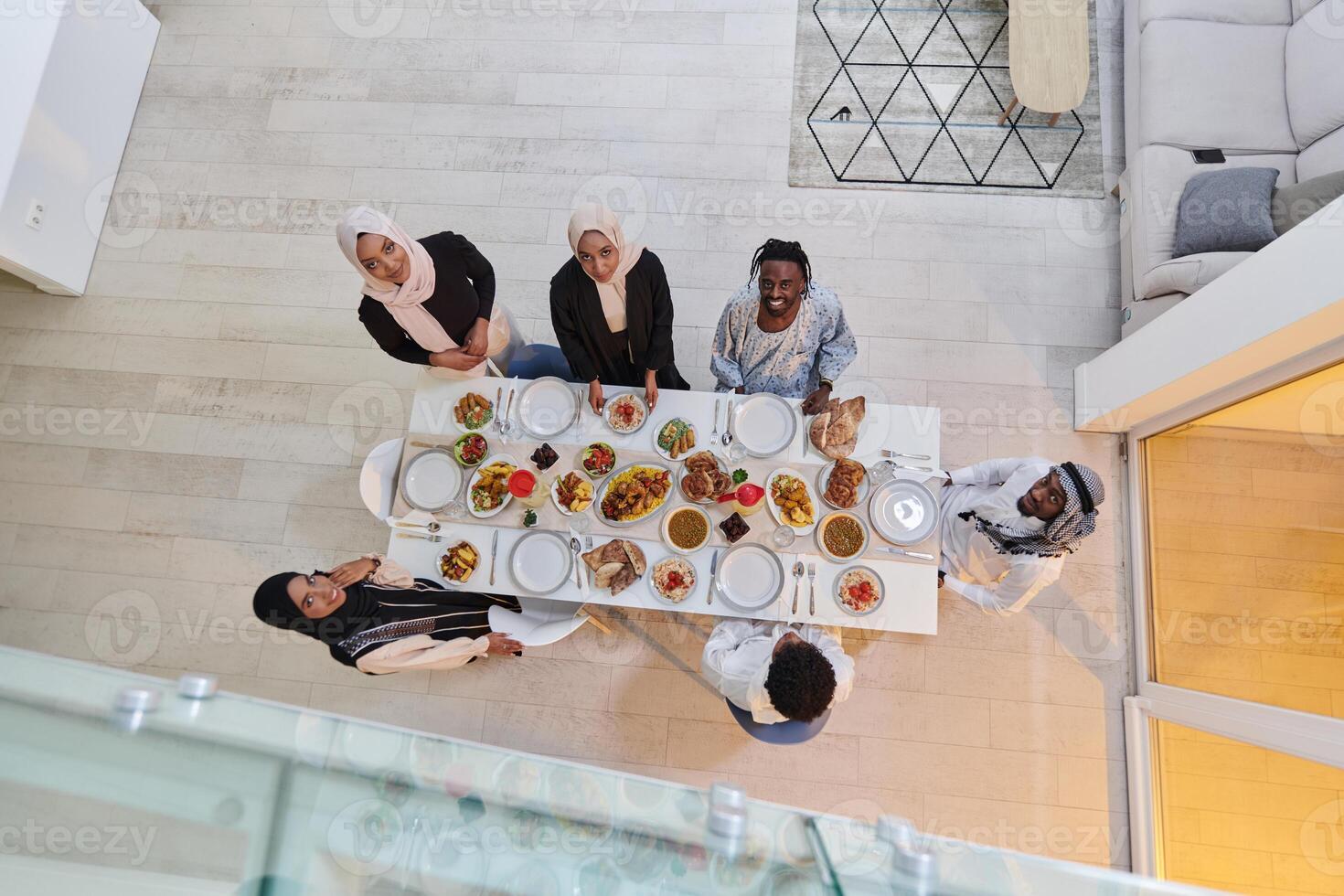 Top view of a Muslim family joyously comes together around a table, eagerly awaiting the communal iftar, engaging in the preparation of a shared meal, and uniting in anticipation of a collective photo