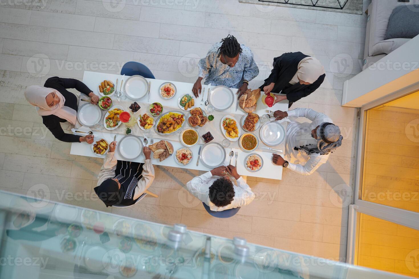 Top view of a Muslim family joyously comes together around a table, eagerly awaiting the communal iftar, engaging in the preparation of a shared meal, and uniting in anticipation of a collective photo