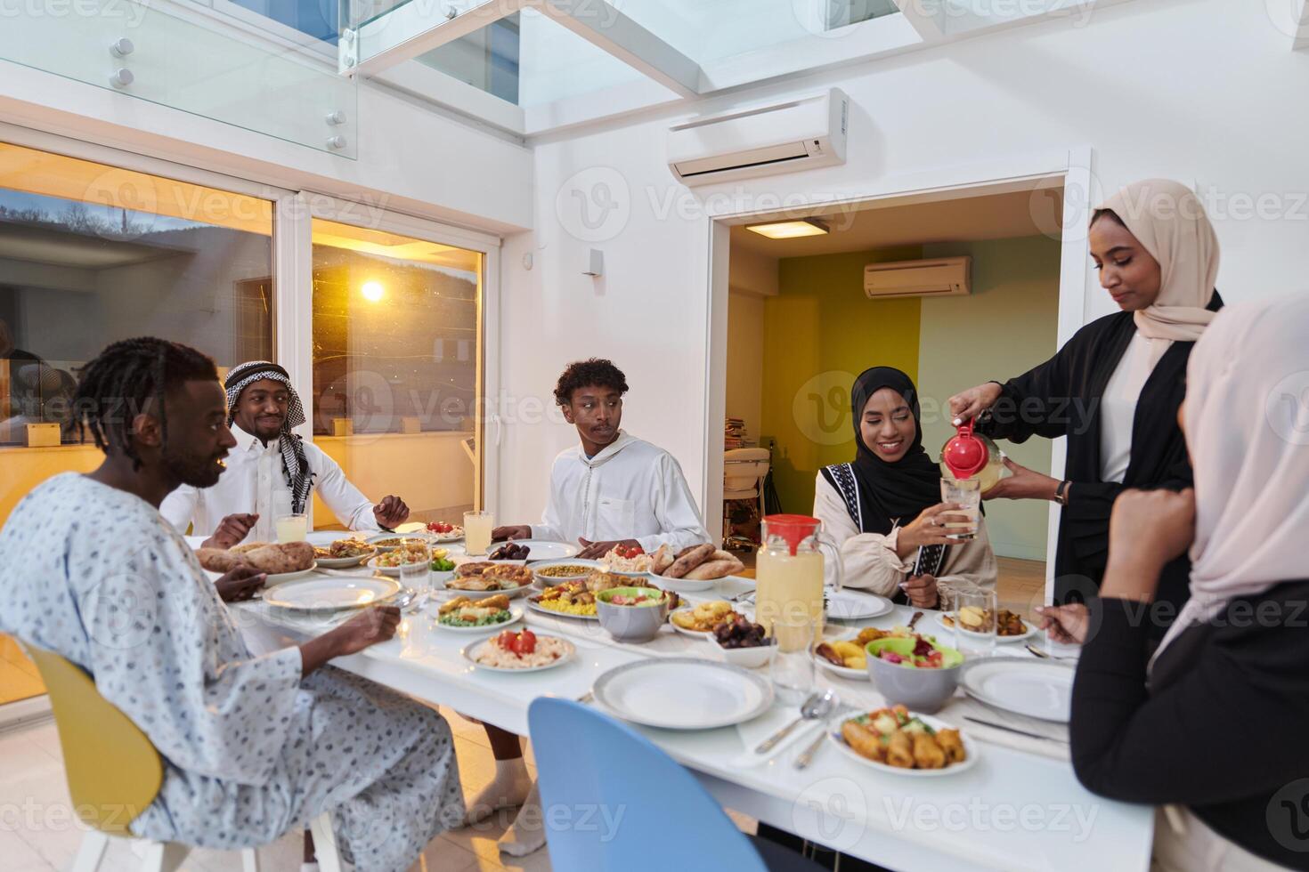 In the sacred month of Ramadan, a Muslim family joyously comes together around a table, eagerly awaiting the communal iftar, engaging in the preparation of a shared meal, and uniting in anticipation photo