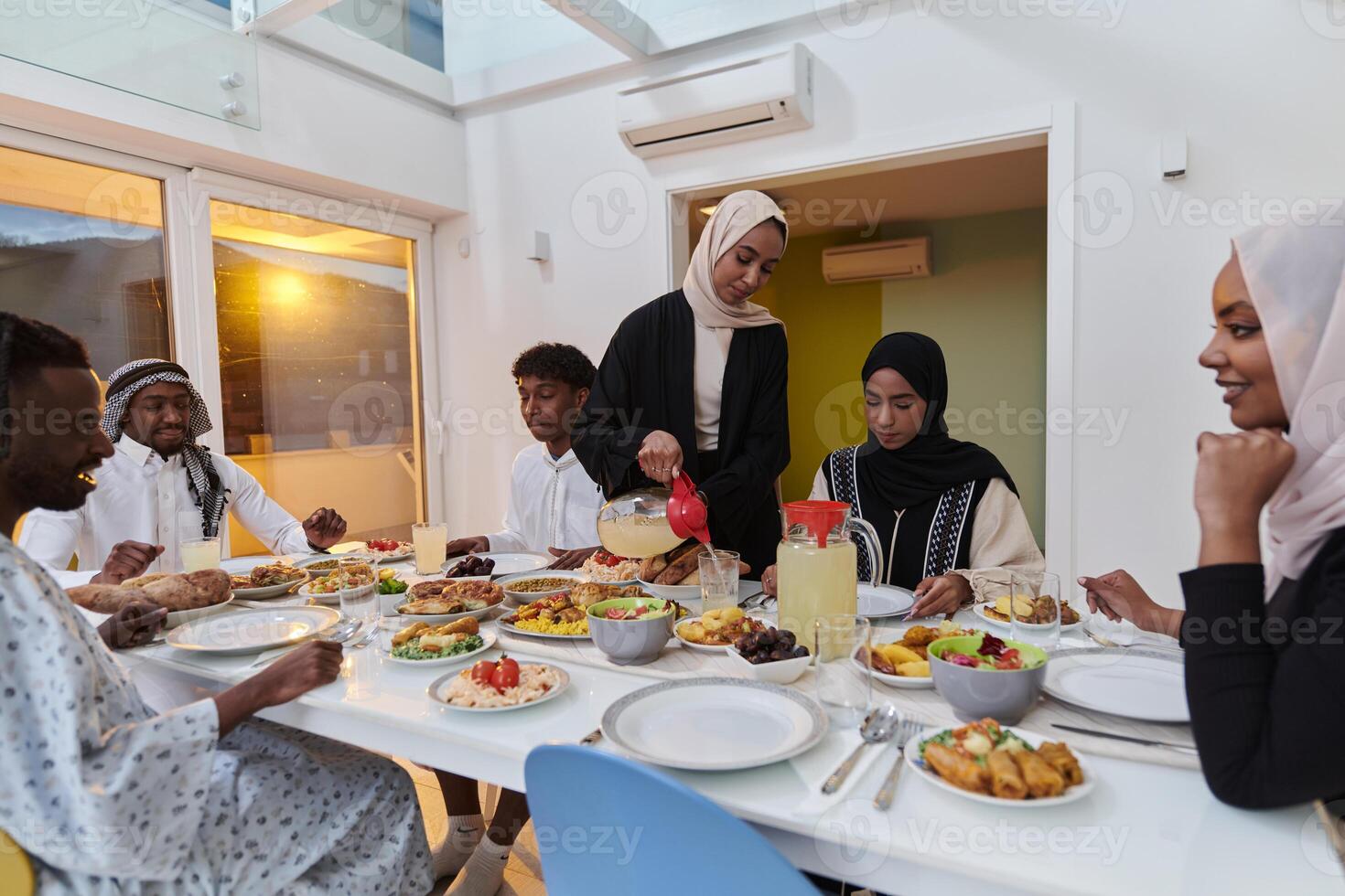 In the sacred month of Ramadan, a Muslim family joyously comes together around a table, eagerly awaiting the communal iftar, engaging in the preparation of a shared meal, and uniting in anticipation photo