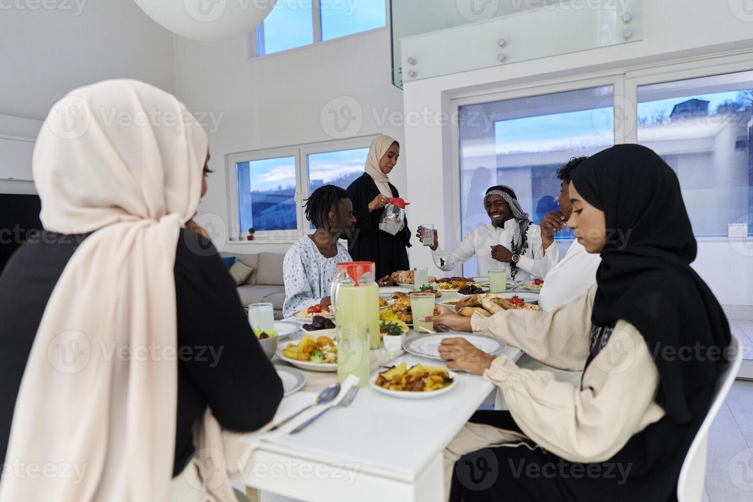 In the sacred month of Ramadan, a Muslim family joyously comes together around a table, eagerly awaiting the communal iftar, engaging in the preparation of a shared meal, and uniting in anticipation photo