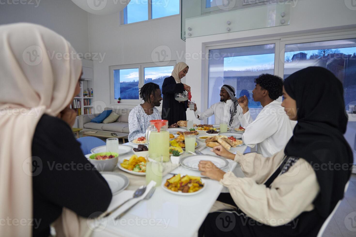In the sacred month of Ramadan, a Muslim family joyously comes together around a table, eagerly awaiting the communal iftar, engaging in the preparation of a shared meal, and uniting in anticipation photo