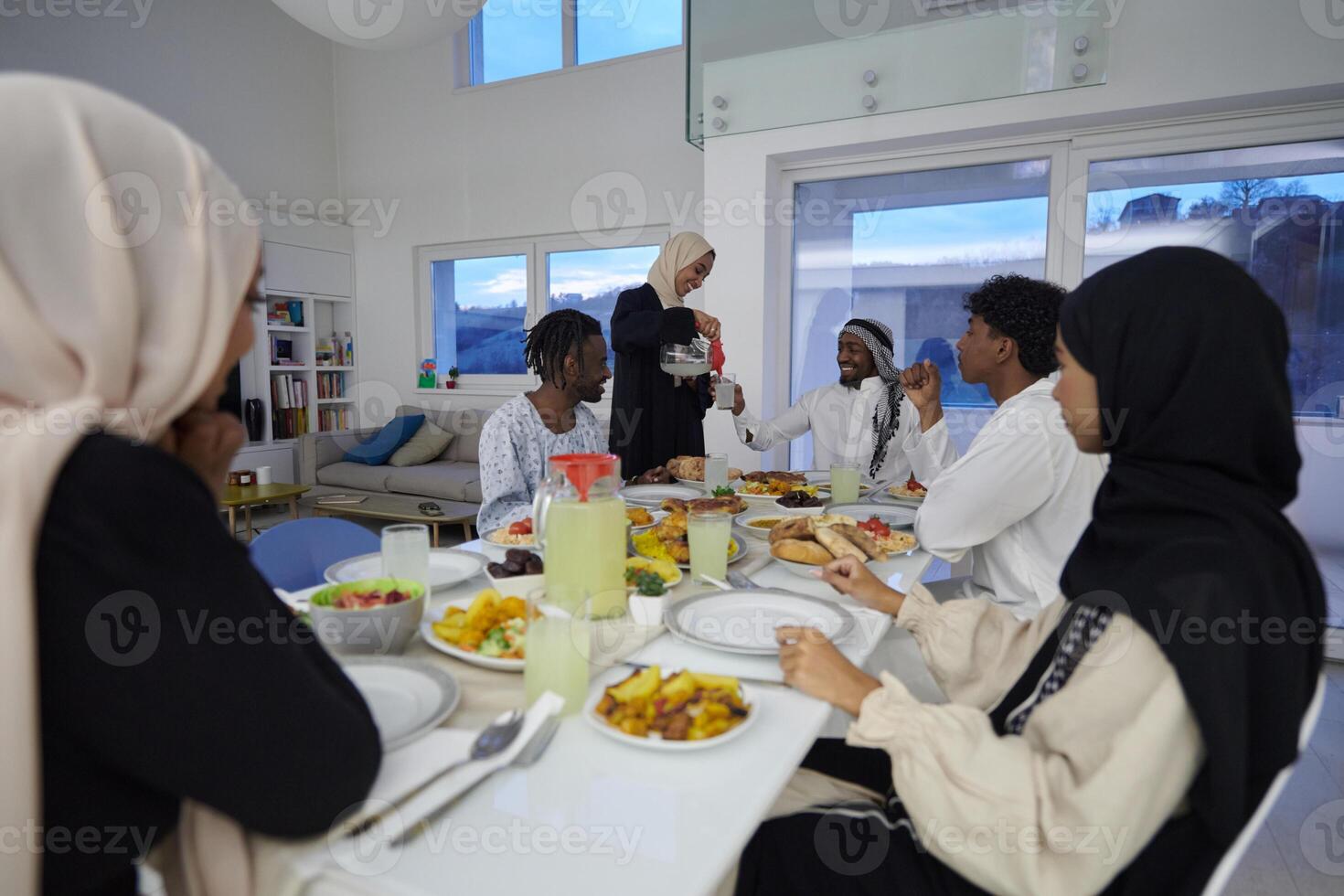 In the sacred month of Ramadan, a Muslim family joyously comes together around a table, eagerly awaiting the communal iftar, engaging in the preparation of a shared meal, and uniting in anticipation photo