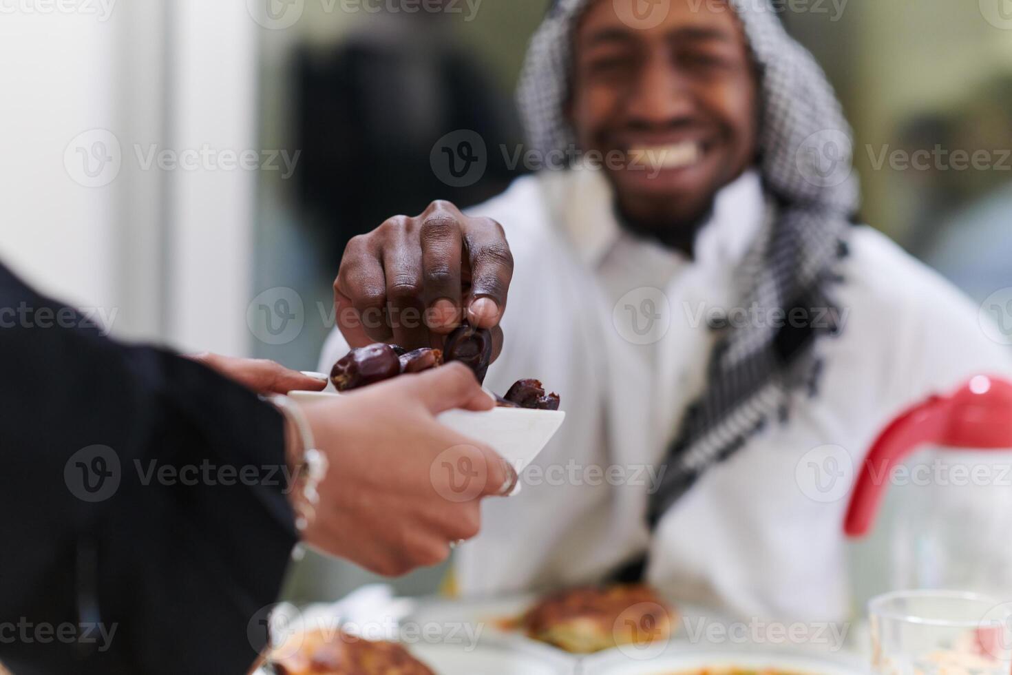African American Muslim man delicately takes dates to break his fast during the Ramadan month, seated at the family dinner table, embodying a scene of spiritual reflection, cultural tradition, and the photo