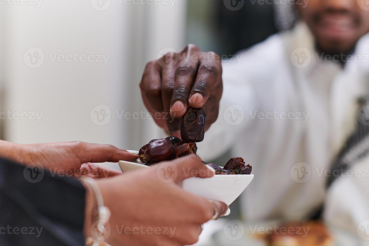 African American Muslim man delicately takes dates to break his fast during the Ramadan month, seated at the family dinner table, embodying a scene of spiritual reflection, cultural tradition, and the photo