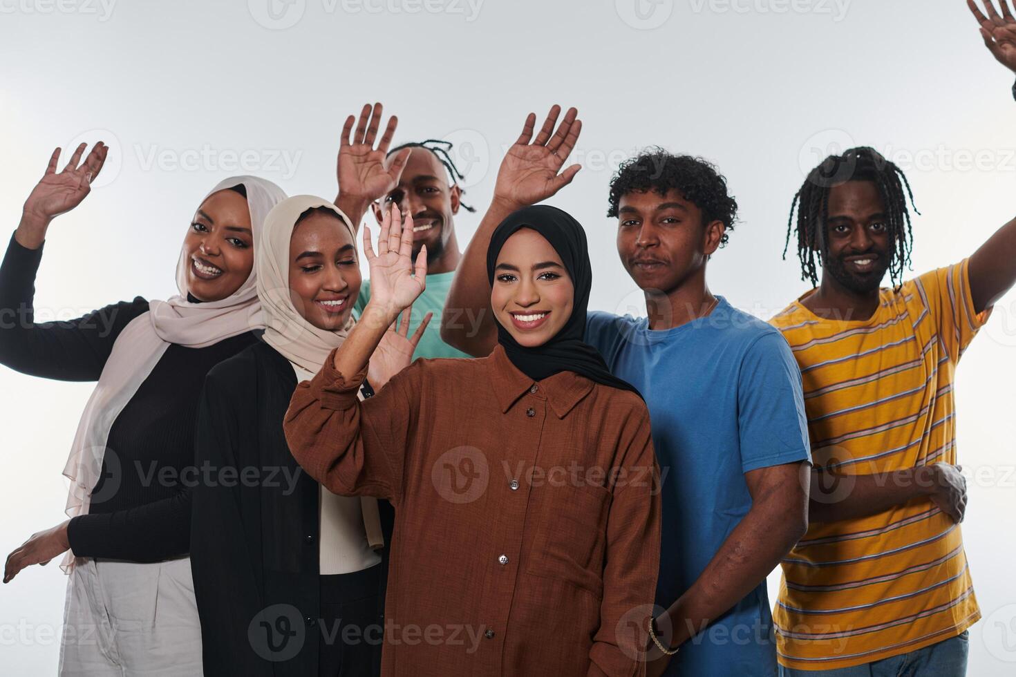 A jubilant and diverse group, including an African American man and hijab-wearing girls, exuberantly wave and celebrate, embodying the vibrancy of student life against a white backdrop, symbolizing photo