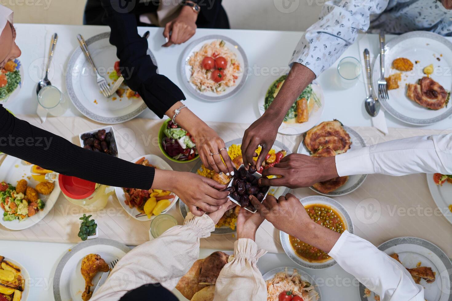 Top view of diverse hands of a Muslim family delicately grasp fresh dates, symbolizing the breaking of the fast during the holy month of Ramadan, capturing a moment of cultural unity, shared tradition photo