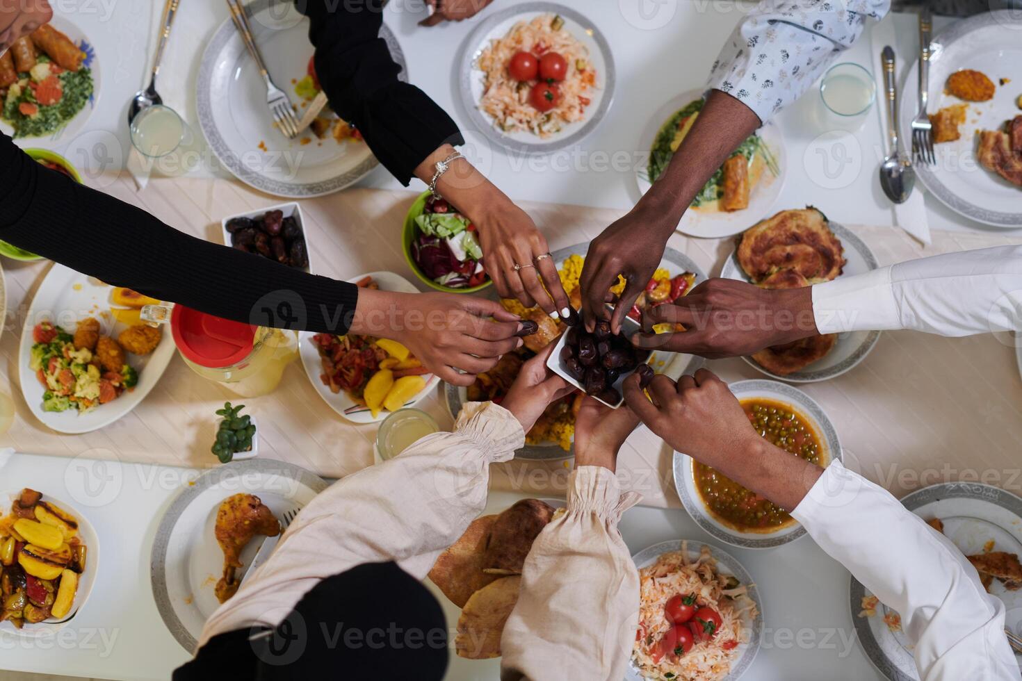 Top view of diverse hands of a Muslim family delicately grasp fresh dates, symbolizing the breaking of the fast during the holy month of Ramadan, capturing a moment of cultural unity, shared tradition photo