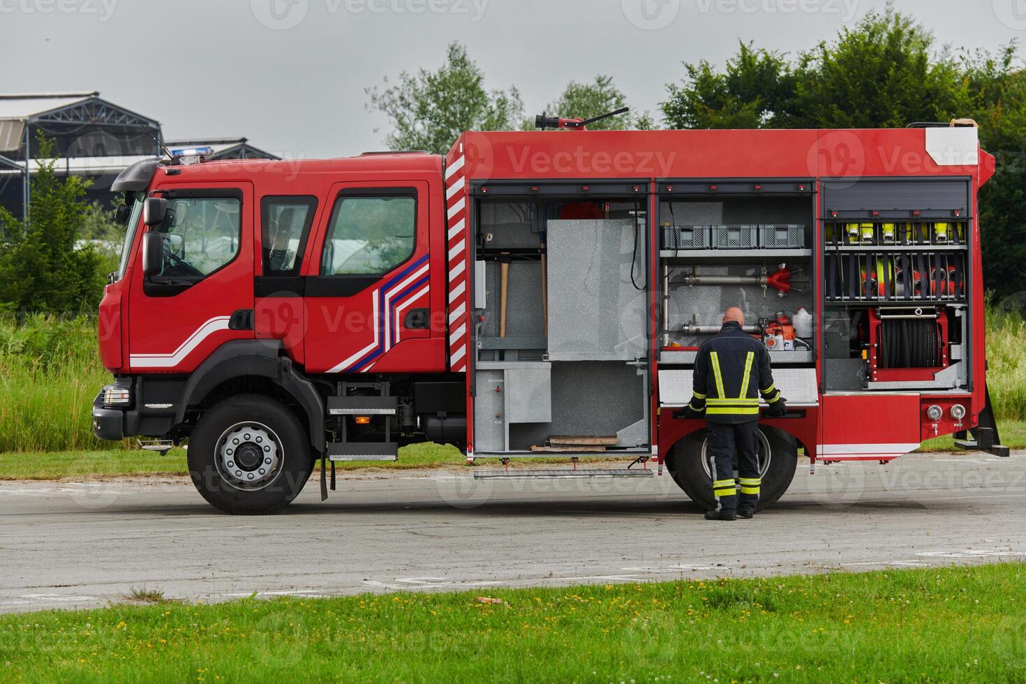 A firefighter meticulously prepares a modern firetruck for a mission to evacuate and respond to dangerous situations, showcasing the utmost dedication to safety and readiness in the face of a fire photo