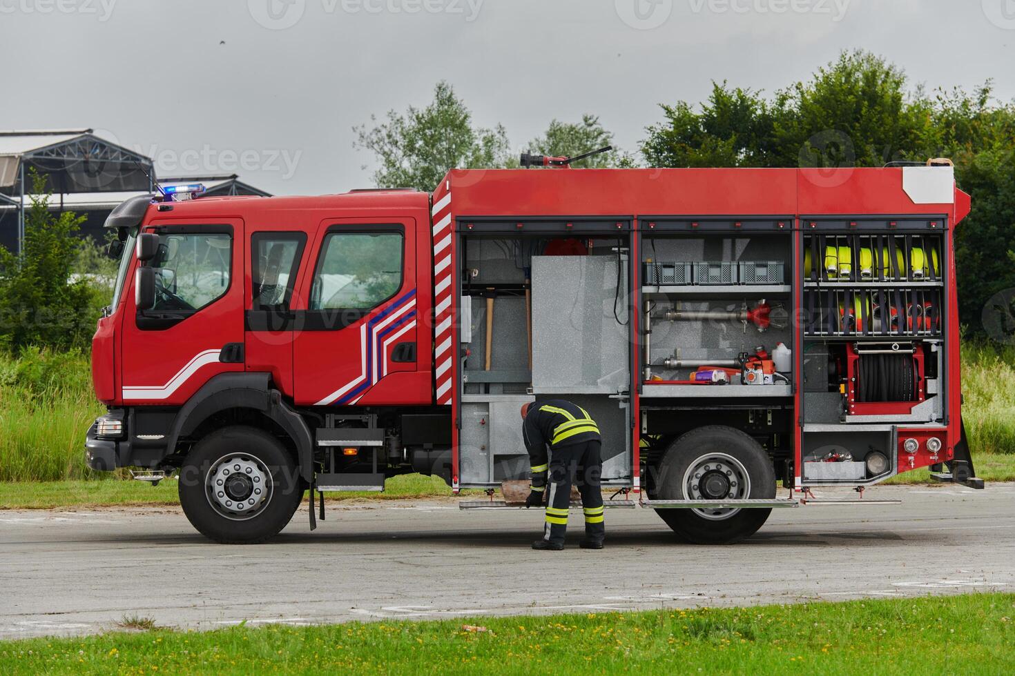 A firefighter meticulously prepares a modern firetruck for a mission to evacuate and respond to dangerous situations, showcasing the utmost dedication to safety and readiness in the face of a fire photo