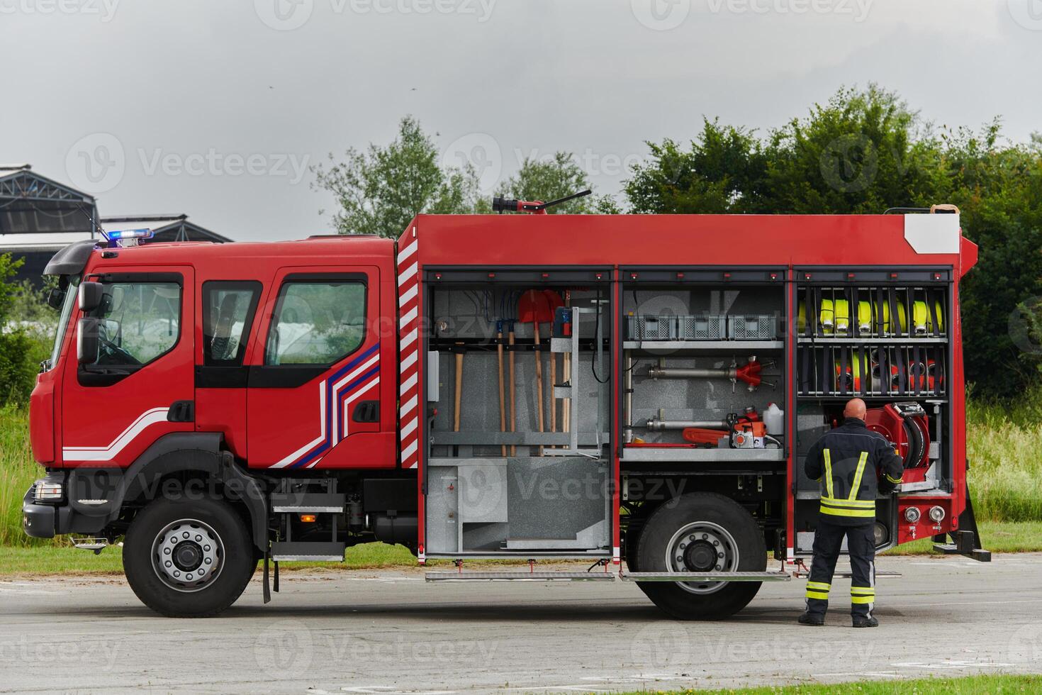 A firefighter meticulously prepares a modern firetruck for a mission to evacuate and respond to dangerous situations, showcasing the utmost dedication to safety and readiness in the face of a fire photo