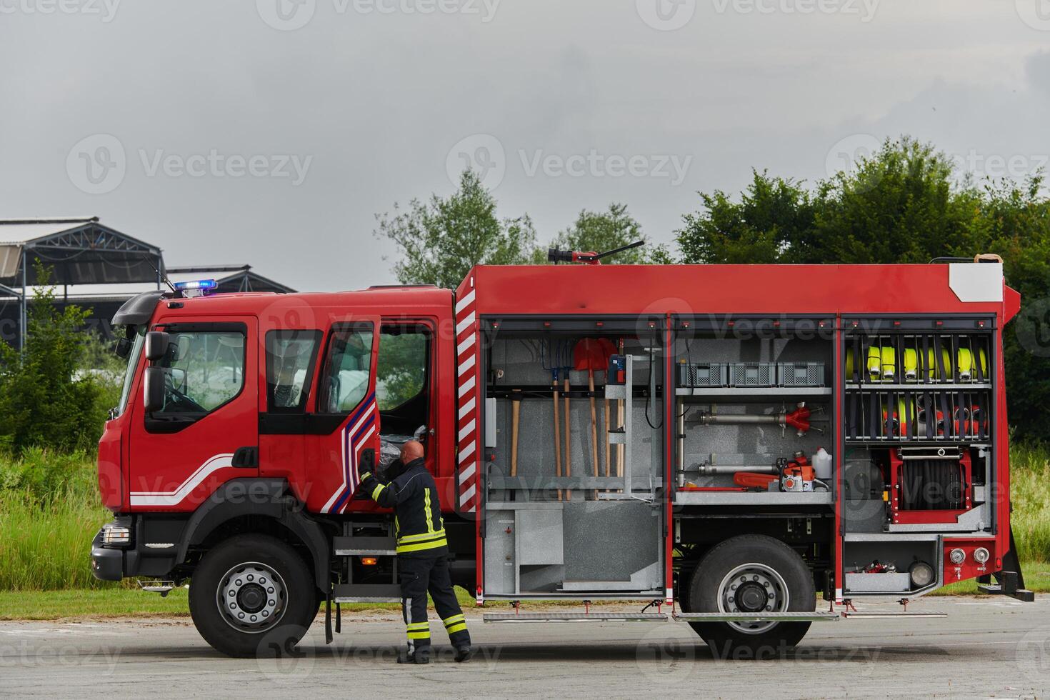A firefighter meticulously prepares a modern firetruck for a mission to evacuate and respond to dangerous situations, showcasing the utmost dedication to safety and readiness in the face of a fire photo