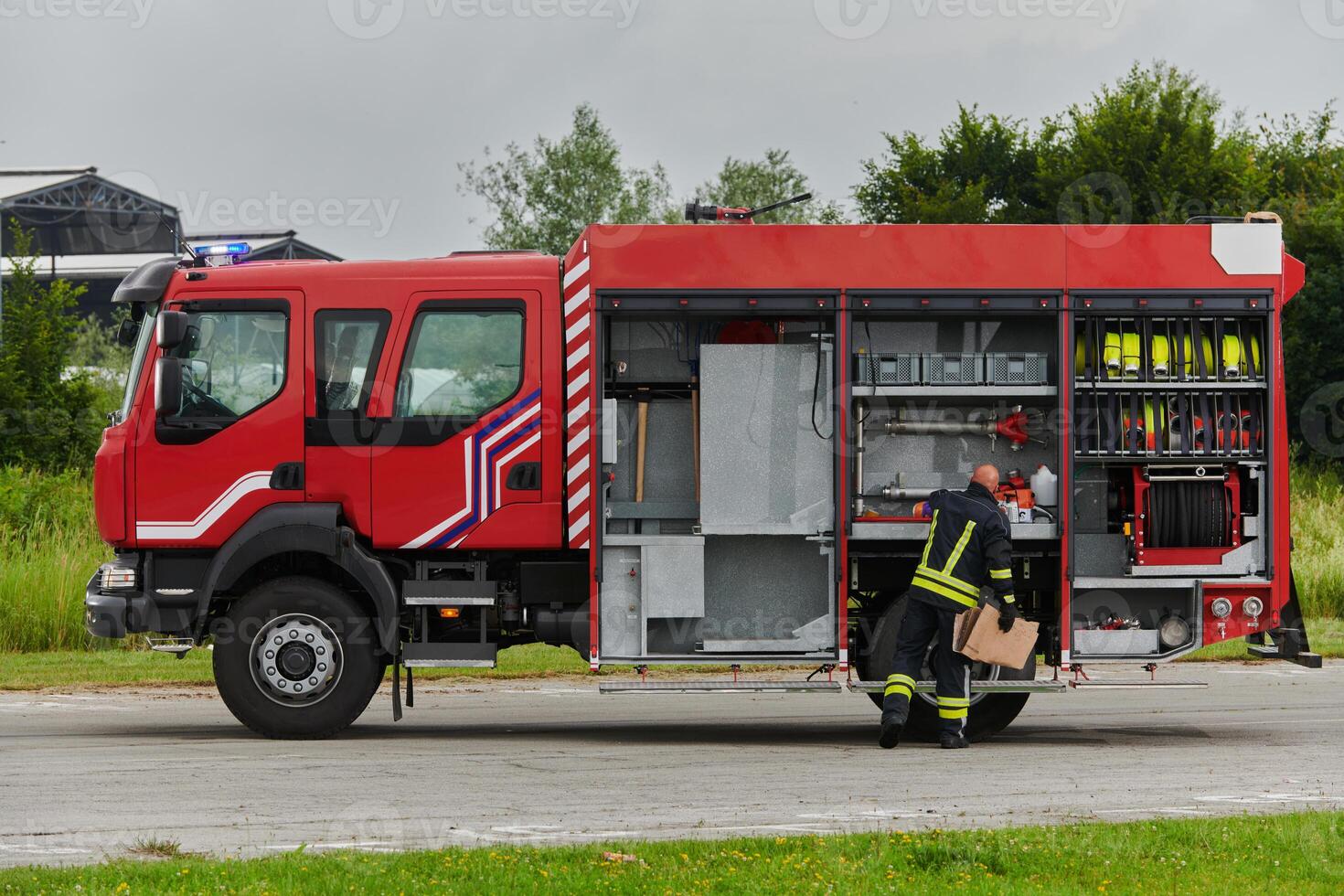 A firefighter meticulously prepares a modern firetruck for a mission to evacuate and respond to dangerous situations, showcasing the utmost dedication to safety and readiness in the face of a fire photo