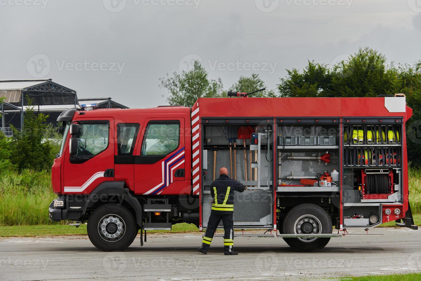 A firefighter meticulously prepares a modern firetruck for a mission to evacuate and respond to dangerous situations, showcasing the utmost dedication to safety and readiness in the face of a fire photo