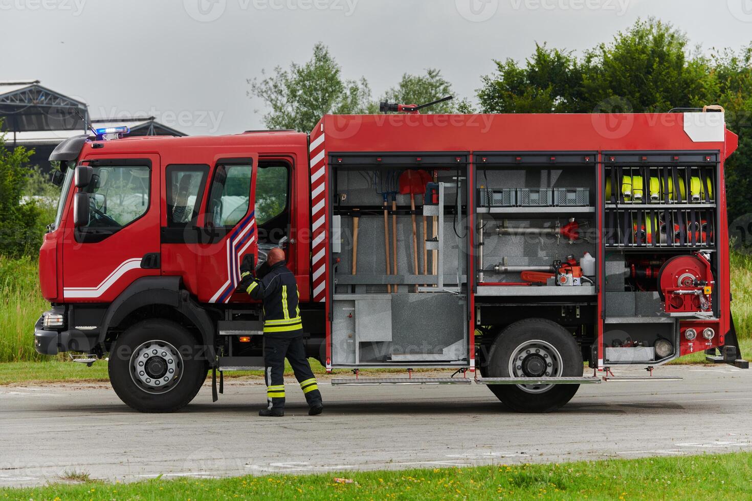 A firefighter meticulously prepares a modern firetruck for a mission to evacuate and respond to dangerous situations, showcasing the utmost dedication to safety and readiness in the face of a fire photo