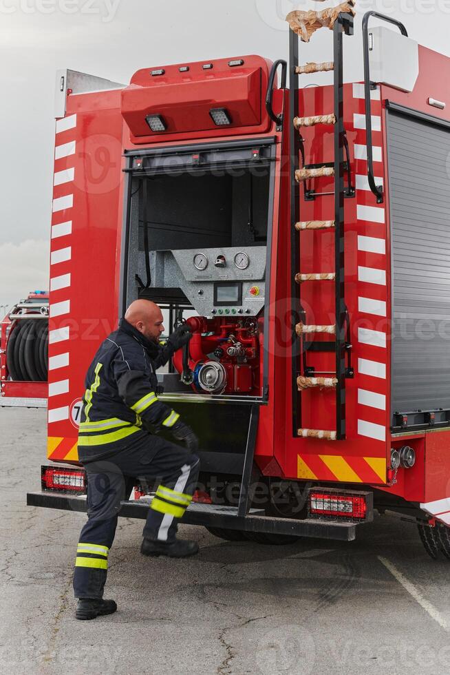 A firefighter meticulously prepares a modern firetruck for a mission to evacuate and respond to dangerous situations, showcasing the utmost dedication to safety and readiness in the face of a fire photo