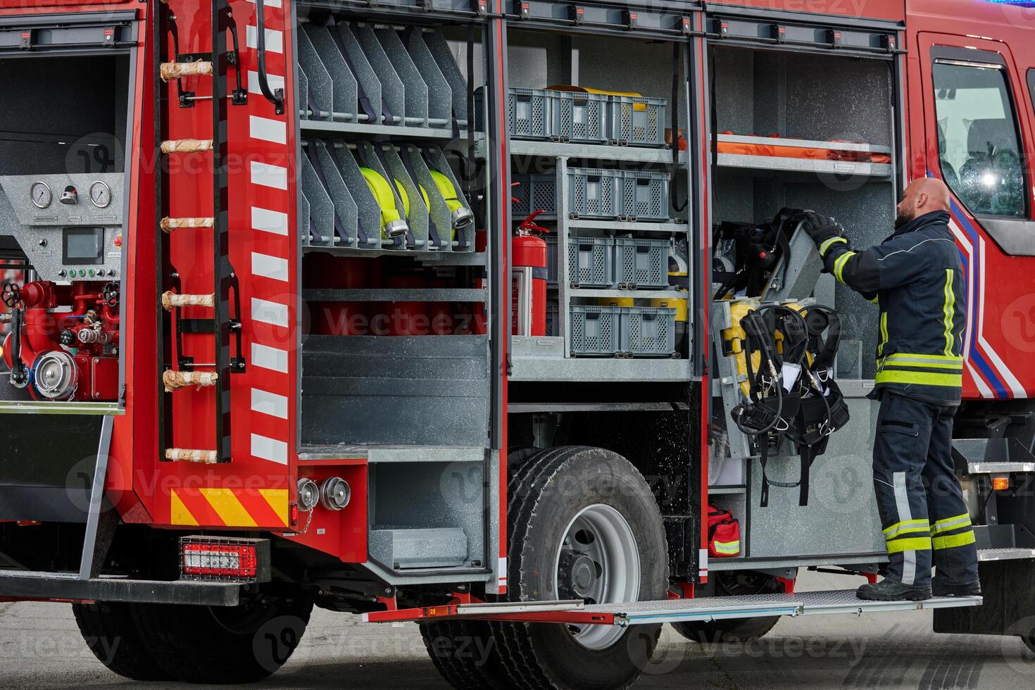 A firefighter meticulously prepares a modern firetruck for a mission to evacuate and respond to dangerous situations, showcasing the utmost dedication to safety and readiness in the face of a fire photo