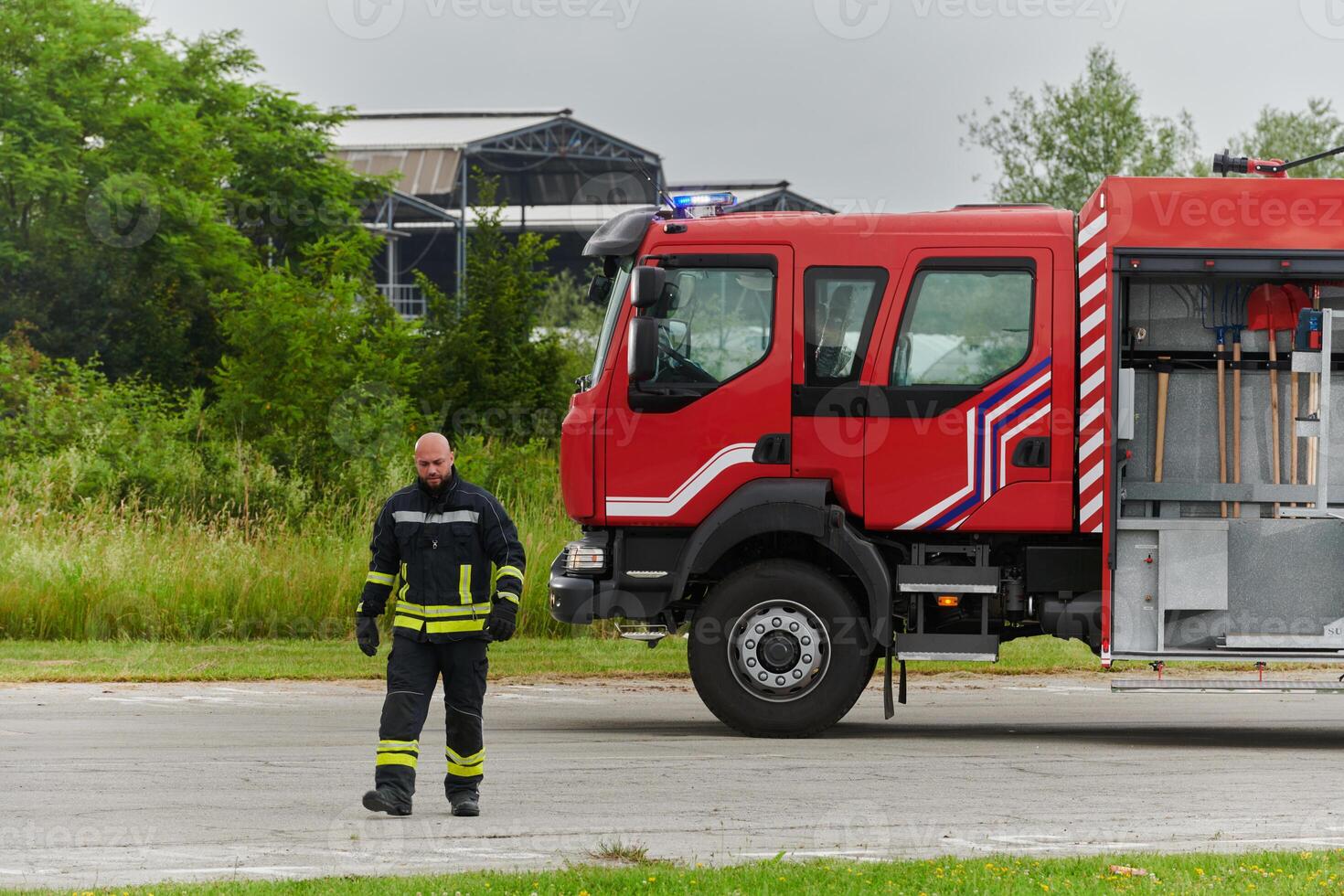 A symbolically brave firefighter strides forward with unwavering courage, epitomizing dedication and leadership, while behind him, a modern firetruck stands ready for firefighting actions, capturing photo