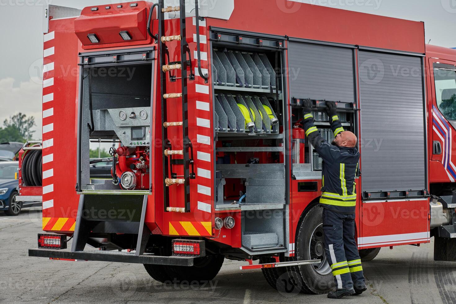 A firefighter meticulously prepares a modern firetruck for a mission to evacuate and respond to dangerous situations, showcasing the utmost dedication to safety and readiness in the face of a fire photo