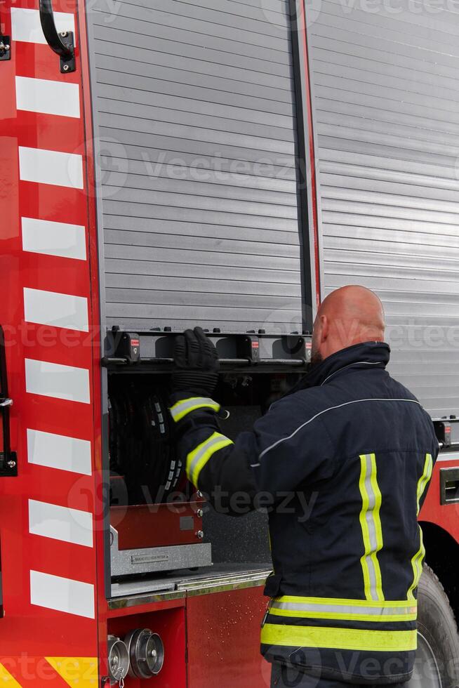 A firefighter meticulously prepares a modern firetruck for a mission to evacuate and respond to dangerous situations, showcasing the utmost dedication to safety and readiness in the face of a fire photo