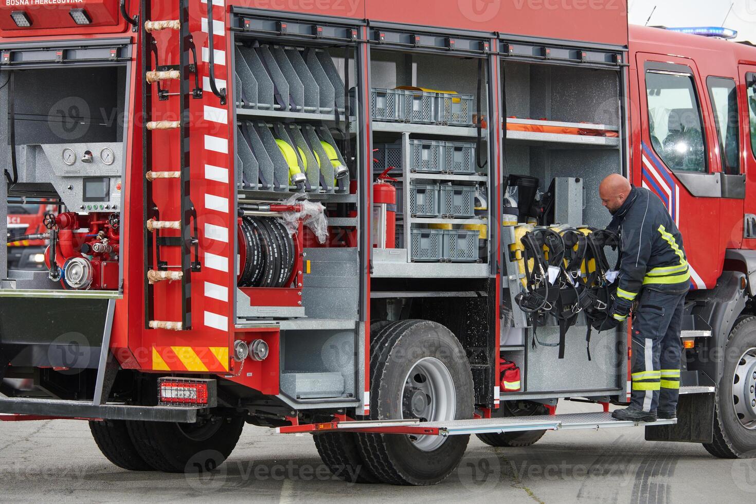 A firefighter meticulously prepares a modern firetruck for a mission to evacuate and respond to dangerous situations, showcasing the utmost dedication to safety and readiness in the face of a fire photo