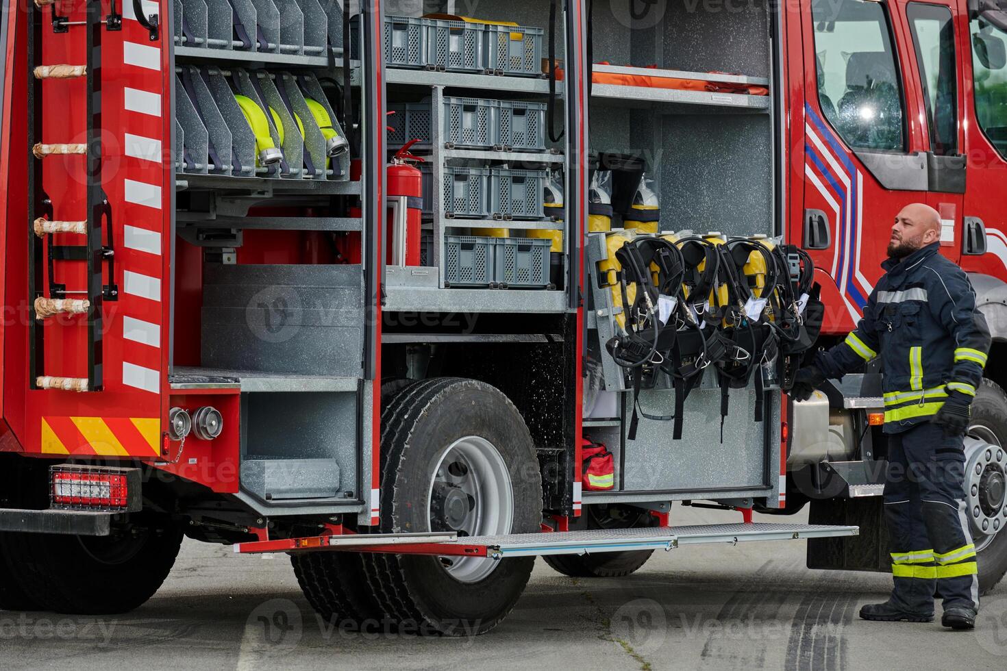 A firefighter meticulously prepares a modern firetruck for a mission to evacuate and respond to dangerous situations, showcasing the utmost dedication to safety and readiness in the face of a fire photo