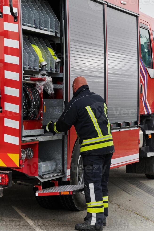 A firefighter meticulously prepares a modern firetruck for a mission to evacuate and respond to dangerous situations, showcasing the utmost dedication to safety and readiness in the face of a fire photo