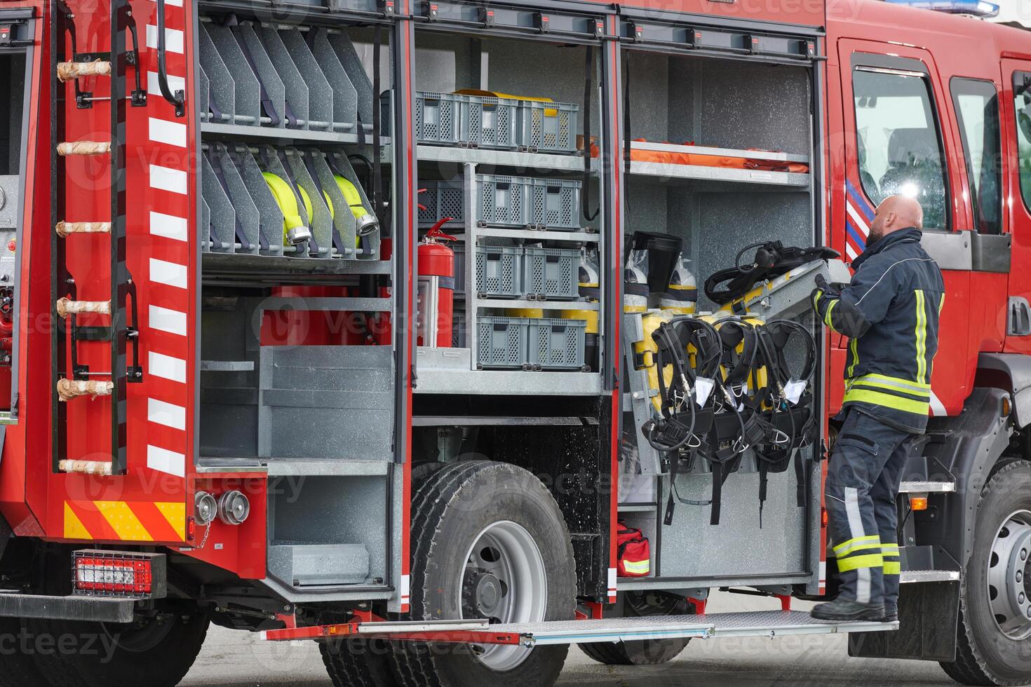 A firefighter meticulously prepares a modern firetruck for a mission to evacuate and respond to dangerous situations, showcasing the utmost dedication to safety and readiness in the face of a fire photo