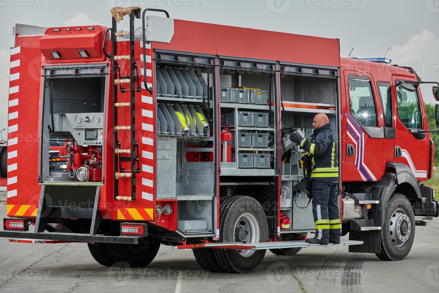 A firefighter meticulously prepares a modern firetruck for a mission to evacuate and respond to dangerous situations, showcasing the utmost dedication to safety and readiness in the face of a fire photo