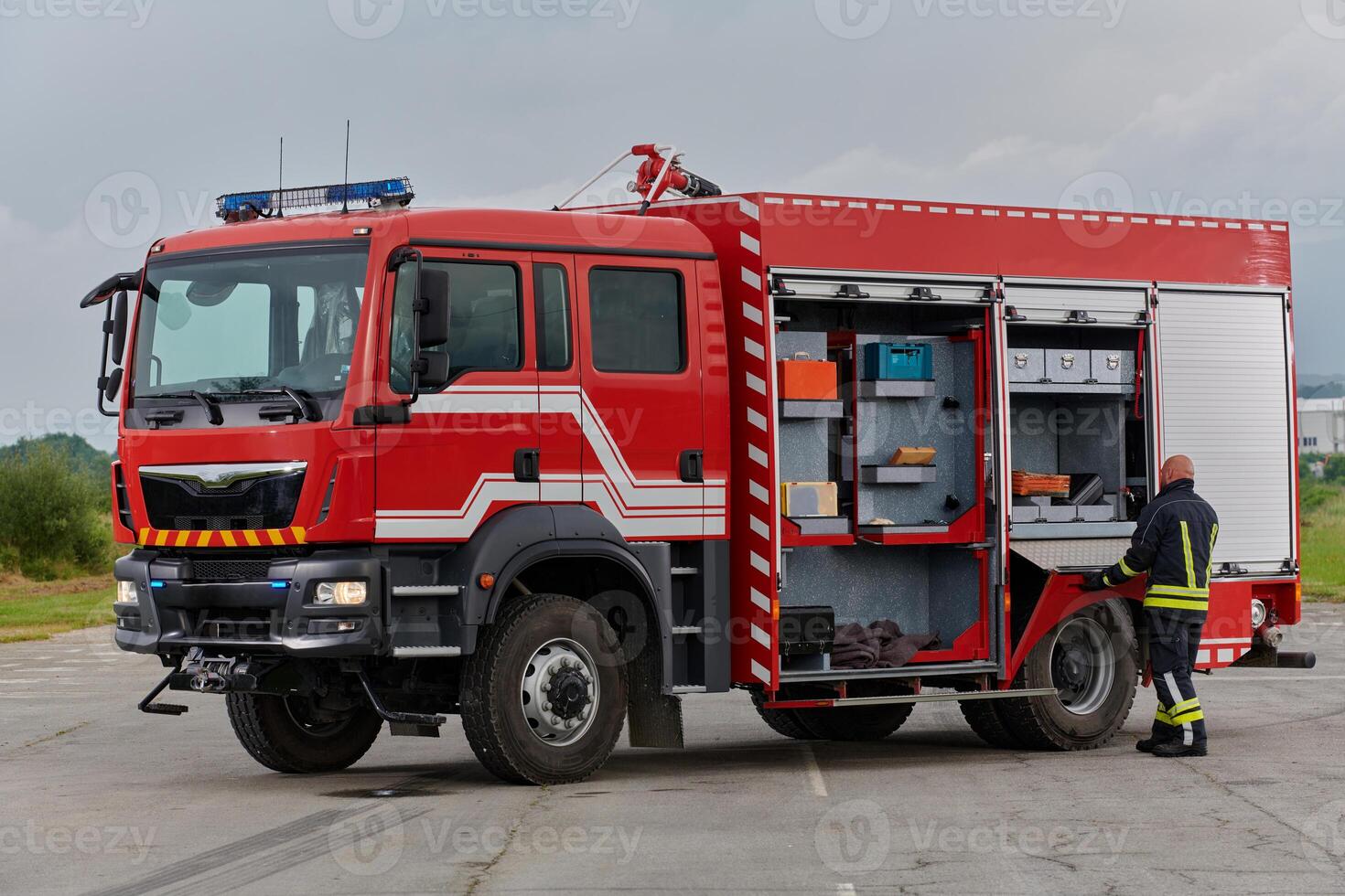 A firefighter meticulously prepares a modern firetruck for a mission to evacuate and respond to dangerous situations, showcasing the utmost dedication to safety and readiness in the face of a fire photo