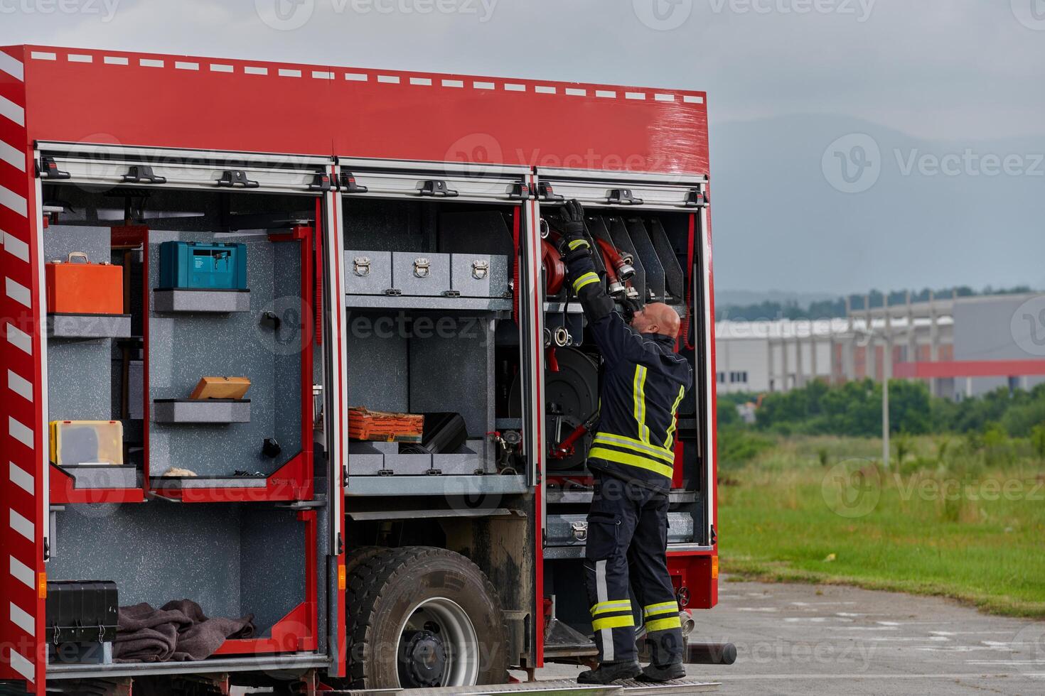 A firefighter meticulously prepares a modern firetruck for a mission to evacuate and respond to dangerous situations, showcasing the utmost dedication to safety and readiness in the face of a fire photo