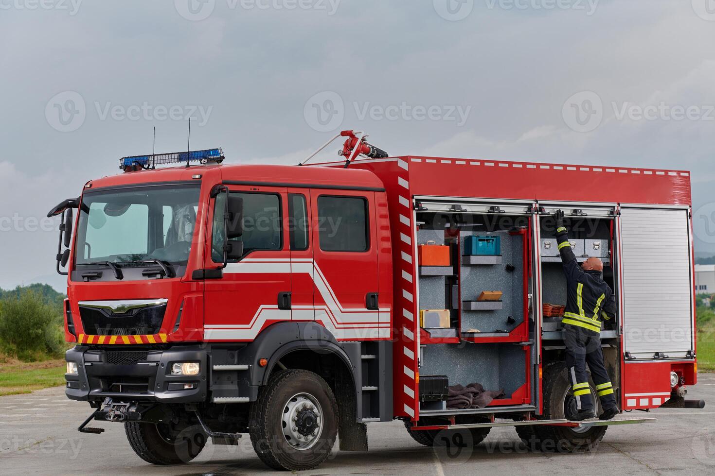 A firefighter meticulously prepares a modern firetruck for a mission to evacuate and respond to dangerous situations, showcasing the utmost dedication to safety and readiness in the face of a fire photo