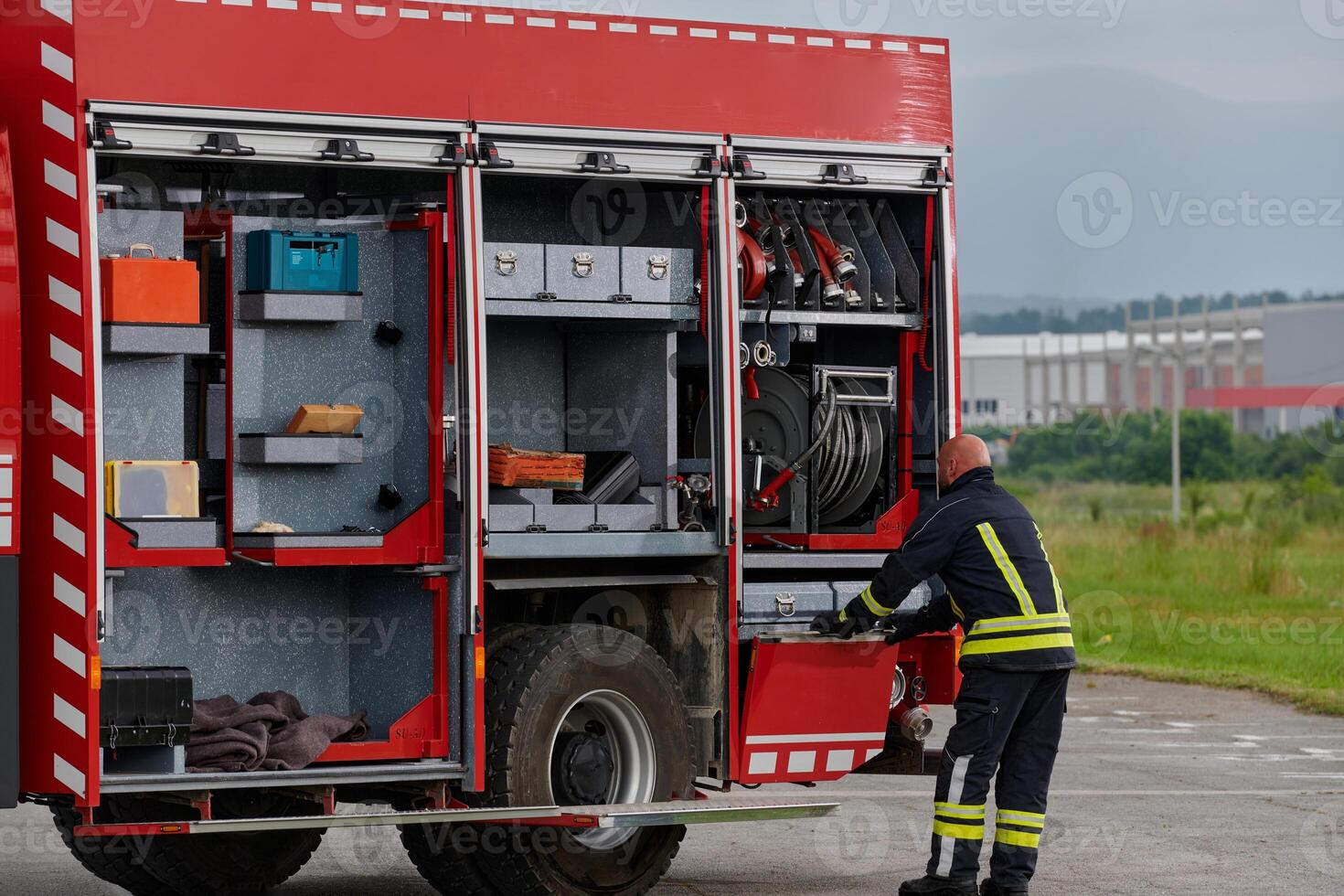 A firefighter meticulously prepares a modern firetruck for a mission to evacuate and respond to dangerous situations, showcasing the utmost dedication to safety and readiness in the face of a fire photo