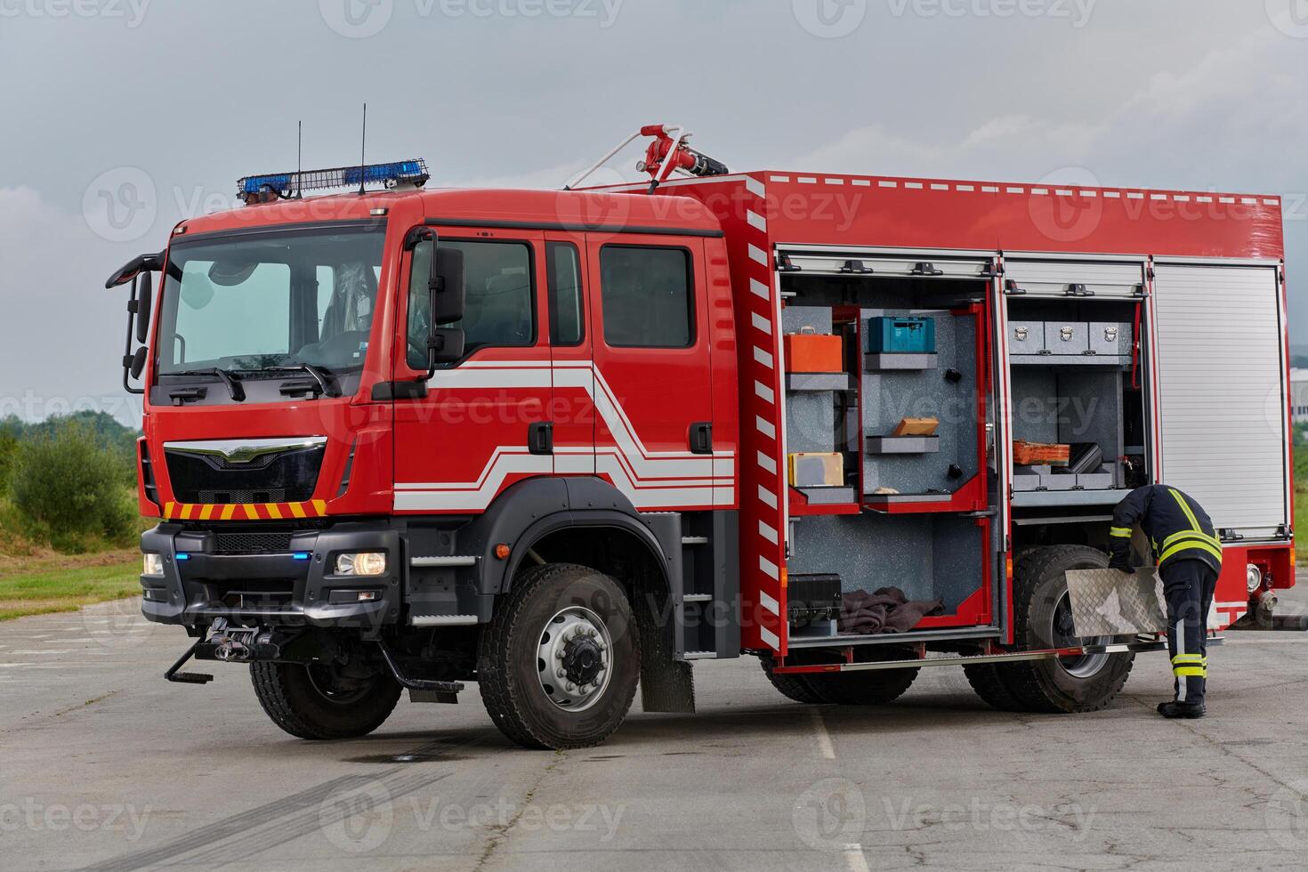 A firefighter meticulously prepares a modern firetruck for a mission to evacuate and respond to dangerous situations, showcasing the utmost dedication to safety and readiness in the face of a fire photo
